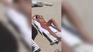 Amazing woman with nice body and shaved wet pussy is sunbathing on the beach