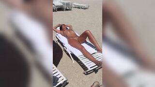 Amazing woman with nice body and shaved wet pussy is sunbathing on the beach